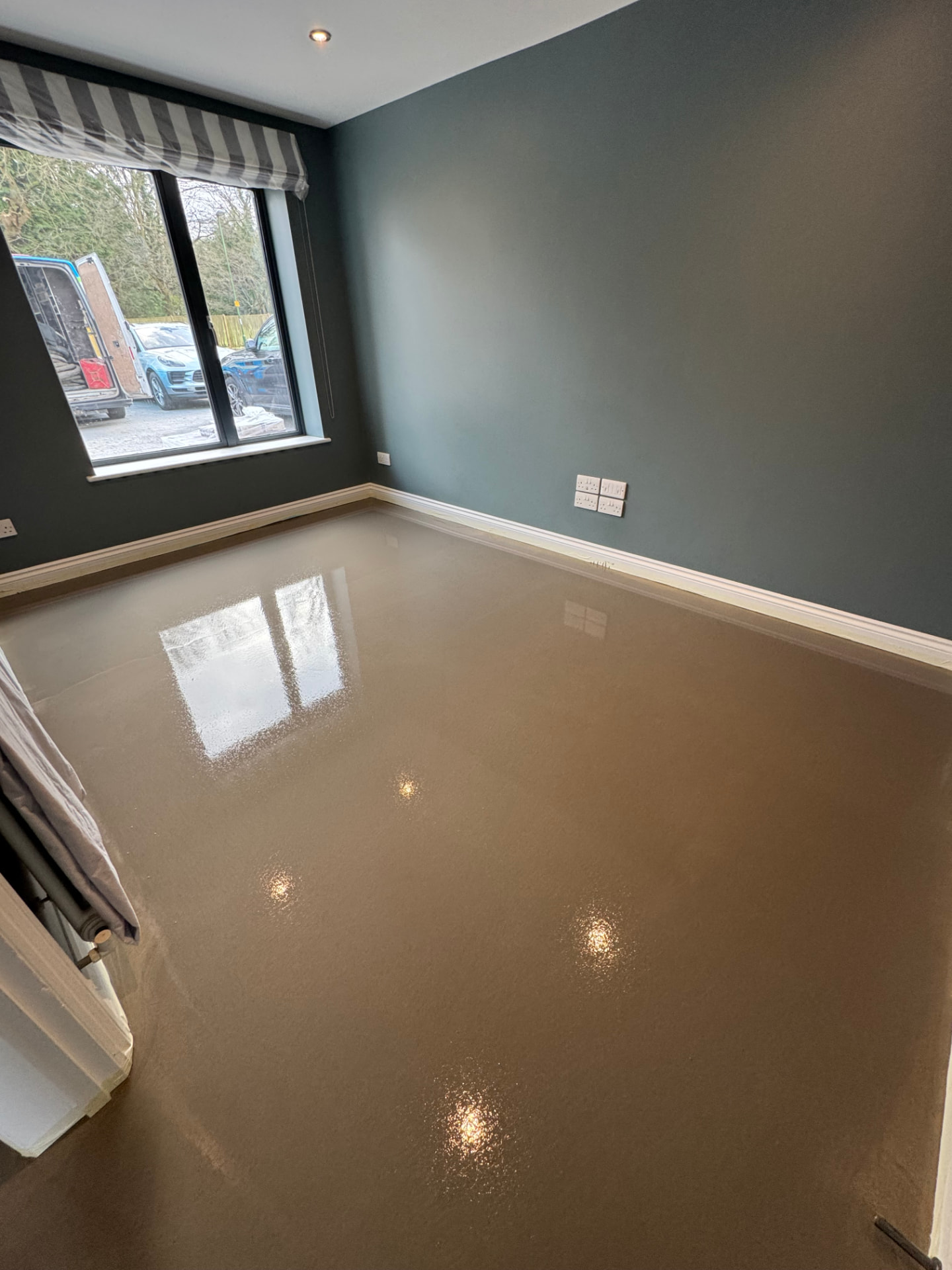 Reflective screed finish in a modern room with large windows