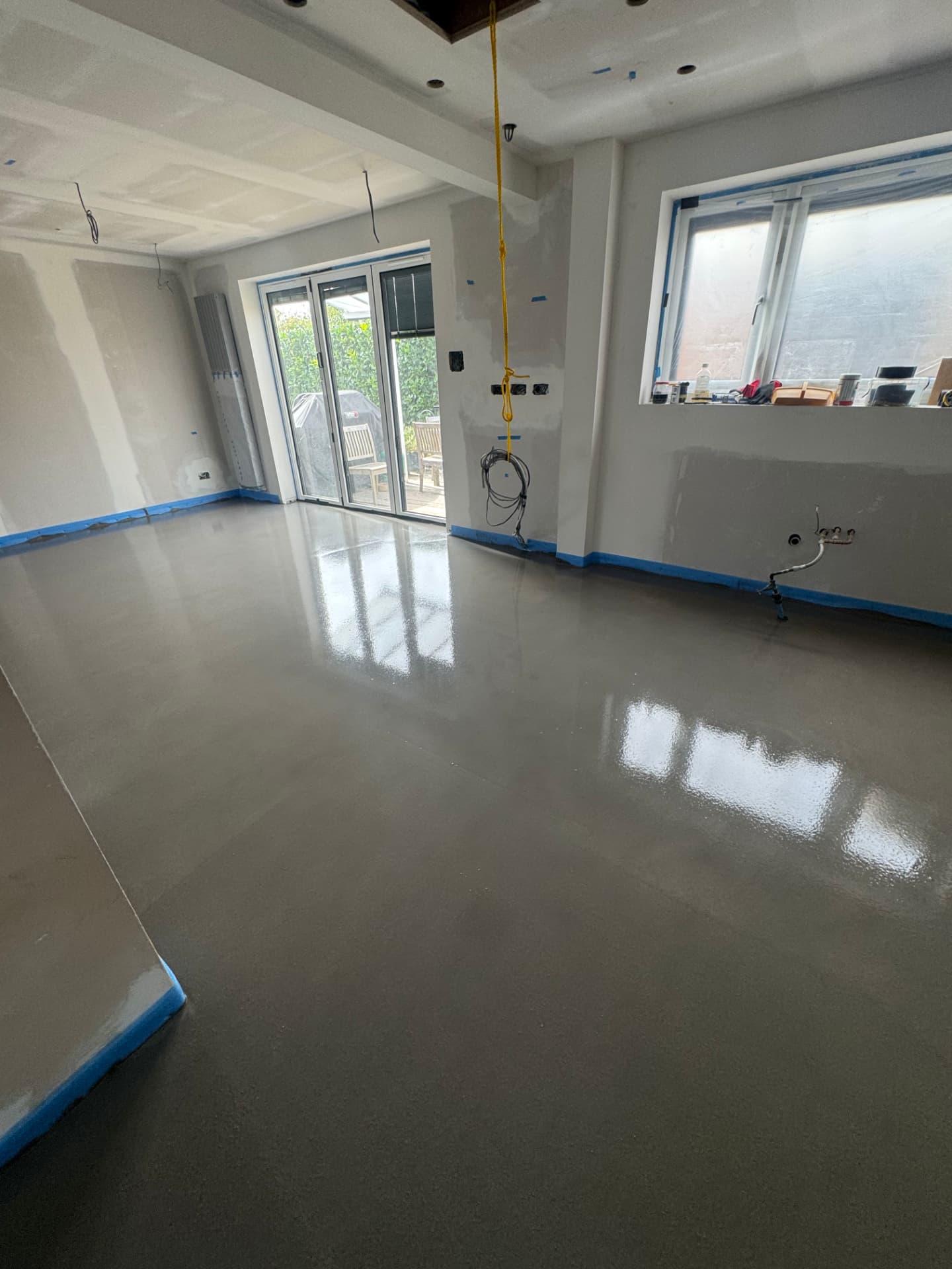 Freshly levelled grey floor in a bright extension with patio doors